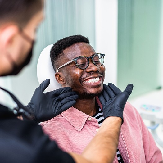 Dentist looking at smiling patient&rsquo;s teeth