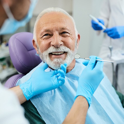 Dentist looking at patient&rsquo;s teeth in treatment chair